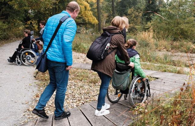 The picture shows wheelchair users passing a ramp in nature.
